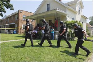 Members of the Toledo Police Department SWAT prepare to move into the home on Bricker Avenue as neighborhood residents watch the action.