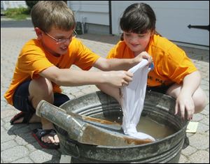 Nicholas Abbott, 8, of Oregon and Haley Jones, 8, of Millbury do laundry on a washboard in a tub at the camp sponsored by the Oregon-Jerusalem Historical Society. It was at the society's museum complex.