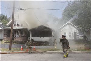 Toledo Fire & Rescue work to put out a fire at 1346 Utah. The fire caused damage to the two homes that flanked its sides.