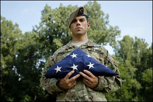 Ranger Kyle Bradley holds one of the flags he carried during deployments to Afghanistan. The Sylvania native will be presenting the flag 'With Valor' to the Fulton County Fireman's Association today at the Mud Hens game.