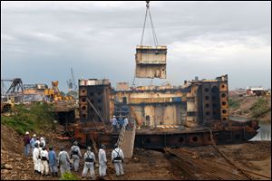 A crew waits for removal of a piece of a scrapped private vessel at the Port of Brownsville, Texas, in February. The company doing the work also dismantles Navy ships.