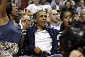 First lady Michelle Obama, from left, President Barack Obama, and daughter Malia Obama react as they watch Team USA and Brazil during the first half of an Olympic exhibition basketball game Monday.