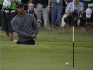 Tiger Woods of the United States watches his chip shot out of the bunker on the 18th green to go on to drop into the hole at Royal Lytham & St Annes golf club during the second round of the British Open Golf Championship, Lytham St Annes, England, Friday.