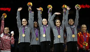 U.S. gymnasts, left to right, Jordyn Wieber, Gabrielle Douglas, McKayla Maroney, Alexandra Raisman, Kyla Ross raise their hands on the podium during the medal ceremony after winning gold medal during today's women's team final.