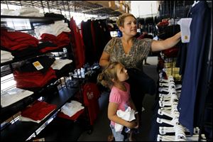 Jen Lawson, of West Toledo, shops for a gym uniform with her six-year-old daughter Aubrey, a first grader at Regina Coeli School, in Schoolbelles Clothing Store.