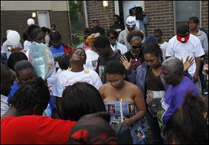 Family and friends of Keondra and Leondra Hooks, including their aunts Tamatha Hamilton, left, and Bernice Neal, center, pray during a vigil at Moody Manor, where the girls were shot late Thursday.