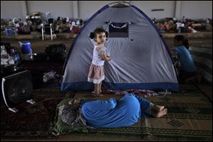 A 3-year-old Syrian girl plays beside the tent her family set up in a shelter near the Turkish border.