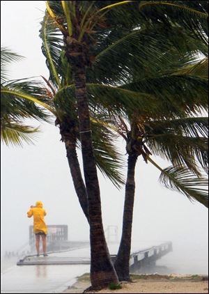 Wind-driven rain batters palm trees and a pedestrian in Key West as Tropical Storm Isaac churns northward. Forecasters warn it could become a Category 2 hurricane.