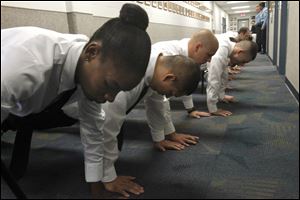 Marquitta Bey, foreground, joins other recruits in doing pushups in the hallway at the Toledo Police Academy law enforcement building at Owens Community College on the first day of training.