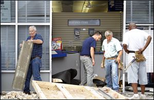 Construction workers remove debris left by a sport utility vehicle that slammed into the front of the U.S. Post Office on Tremainsville Road in West Toledo. One person inside the post office Wednesday was taken to Mercy St. Anne Hospital with injuries — not believed to be life-threatening — from flying debris, according to Toledo fire Lt. Matthew Hertzfeld. The crash of a vehicle into the post office was the second in a little more than three years. In February, 2009, a car smashed into a window. That driver told police she accidentally hit the accelerator instead of the brake. A customer in the lobby suffered minor injuries in that crash.