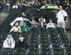 Chicago White Sox fans shelter themselves from the rain and watch a live broadcast of the Bears Green Bay Packers game on the big screen Thursday night during a rain delay between the White Sox and the Detroit Tigers.