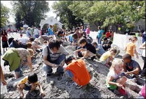 Children and parents swarm the mound of rocks looking for fossils during Fossil Fest on Sunday  at Sylvania Historical Village.