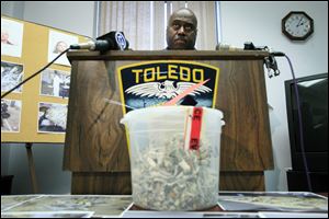 A bucket of mushrooms sits on a table as Toledo Police Chief Derrick Diggs speaks during a press conference about the massive mushroom seizure.