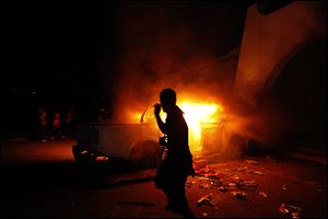 A Libyan civilian watches one of Ansar al-Shariah Brigades cars on fire, after hundreds of Libyans, Libyan Military, and Police raided the Brigades base, in Benghazi, Libya on Friday.