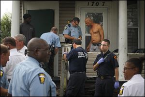 Police interview a man, right, hit by bird shot in a drive-by shooting early Wednesday afternoon at Oakwood Avenue in Toledo. Though injured, he was able to speak with police and walk to an ambulance before leaving for the hospital.