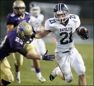 Napoleon High School player Max Westhoven, 21, stiff arms Maumee High School player David McCrum, 23, on his way to a touchdown.