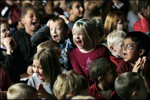 Victoria Sears, center, a first grader at Eagle Point Elementary, cheers for Megan Spangler, her teacher, as they watch Spangler answer questions on Who Wants To Be A Millionaire in the school's gym on Friday.