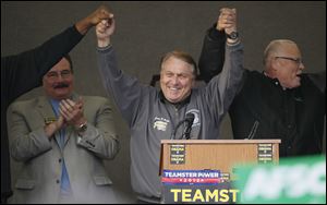 Teamsters General President Jim Hoffa has his hands raised by Al Mixon, left, International Vice-President, and AFSCME President Lee Saunders, right, Thursday after speaking during a rally at Teamsters Local Union 20 in Toledo.  In the background is Bill Lichtenwald, president of Ohio Conference of Teamsters and Local 20.