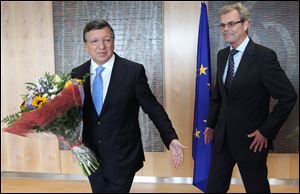 European Commission President Jose Manuel Barroso, left, receives flowers by Norway's ambassador to the EU Atle Leikvoll, after the 2012 Nobel Peace Prize was given to the EU, at the European Commission headquarters in Brussels on Friday.