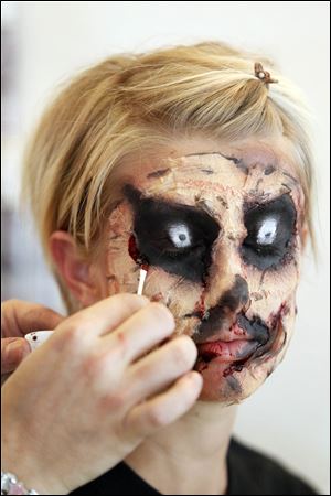 Carl Graf, a professional makeup artist, puts eyes on the eyelids of Mary Beth Lengel.