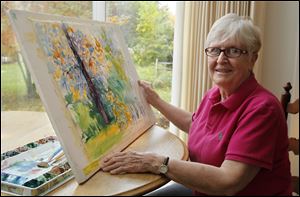 Alice Dewey poses with a partially finished painting at her home in Temperance, Michigan, Thursday.  She will have some of her watercolors in the 23rd annual Arts for Our Future Show at the Bedford library on November 4.