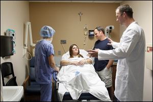 Jamie Barkimer, and her husband, Nate, listen as Dr. Matthew Fourman, right, and nurse Dawn Herr prepare Mrs. Barkimer for surgery.