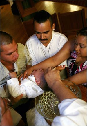 Jose Correa, left, is joined by Daniel and Esmeralda Barrera at the baptism of Mr. Correa’s 2-year-old son, Osbaldo. Mr. Correa was among 101 Latino workers terminated by WinCup in March.