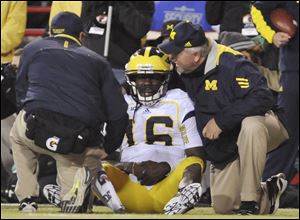 Michigan quarterback Denard Robinson is looked over by Michigan staff members after he was injured in the first half of an NCAA college football game against Nebraska, in Lincoln, Neb.