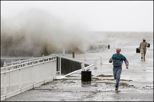 Bill Klaehn, Marblehead, outruns his son George Klaehn, 17, Tuesday after taking pictures of waves crashing over the dock at Lakeside, Ohio.