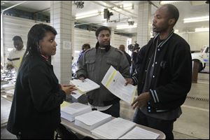 Erica Powell, left, a city of Toledo human resources employee, speaks with Glenn Carter, center, and Michael Hatchett, both of Detroit, at the Michael P. Bell Fire Administration Building about the application process.