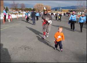 This Nov. 24, 2011 photo courtesy of Kalli Ryti shows her son, Cooper Bourret, racing a turkey to the finish line at the Huffing for Stuffing Thanksgiving Day Run in Bozeman, Mont. Ms. Ryti runs the race with her family every year before enjoying a turkey dinner.  (AP Photo/Courtesy Kalli Ryti, Mike Bourret)