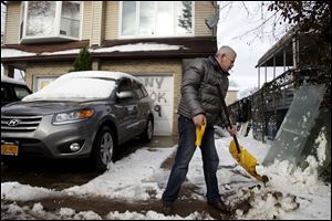 Gennady Naydis keeps clearing his driveway even as the handle breaks off his shovel in the New Dorp section of Staten Island, N.Y., Thursday.