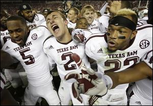 Texas A&M quarterback Johnny Manziel (2) is joined by wide receiver Kenric McNeal (5) and defensive back Dustin Harris (22) as they celebrate a win over top ranked Alabama today at Bryant-Denny Stadium in Tuscaloosa, Ala.