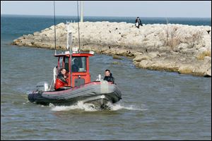 Jerusalem Township Fire Department members return to shore after searching for a boat that capsized on Maumee Bay that had two men on board Sunday.