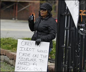 Shena Hardin holds up a sign to serve a highly public sentence Tuesday, Nov. 13, 2012, in Cleveland, for driving on a sidewalk to avoid a Cleveland school bus that was unloading children. A Cleveland Municipal Court judge ordered 32-year-old Hardin to serve the highly public sentence for one hour Tuesday and Wednesday. (AP Photo/Tony Dejak)