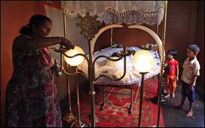 A relative of Asitha Sanjaya Disanayake, a prison inmate who was killed in the recent prison riot, lights a lamp near his body during the burial ceremony, in Colombo, Sri Lanka, Monday.