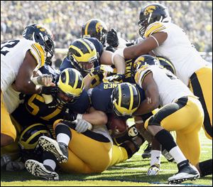 Michigan QB Devin Gardner (12) scores a touchdown against Iowa on a sneak during the first quarter Saturday, at Michigan Stadium in Ann Arbor, Michigan.