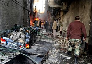 A Syrian soldier, right, and citizens gather at an alley that was destroyed by two cars bombs, at Jaramana neighborhood, in the suburb of Damascus, Syria.