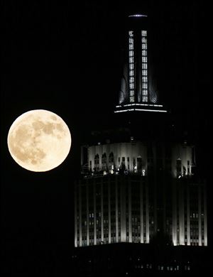 A full moon rises near the Empire State Building, as seen from Hoboken, N.J. on Wednesday.