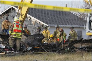 Fire officials use a front end loader to sift through the ruble after a fatal fire near Republic, Ohio.