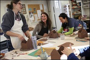 Kristin Perkins, of Oregon, left, jokes with Terri McCullough, of Perrysburg, center, while pottery assistant Nadia Packard, right, takes a look at her clay gingerbread-style house Thursday morning during the Holiday Pottery class at the 577 Foundation in Perrysburg. 