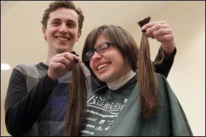 Boyfriend Blake Weible, 23, left, holds the hair of Dakota Lause after the first cuts were made before her head is fully shaved Sunday at BGSU.