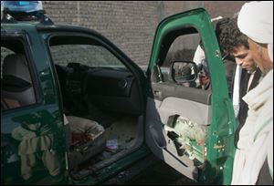 Afghans look at a damaged police vehicle after it was hit by a roadside bomb in Herat, west of Kabul, today.