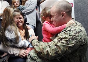 Julie Luffy, left, holds daughter Aubrey Sadowy, 6, while her husband, PO 1st Class Eric Luffy, holds daughter Alivia Luffy after their on-air surprise homecoming at the Star 105 studio in Toledo. Mr. Luffy just returned from seven months’ duty in the United Arab Emirates.