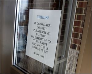 A sign on a door at Elmwood Elementary School in Bloomdale directs visitors to ring a buzzer if the doors are locked.