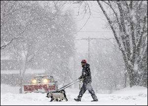 Steve Gordon of Madison, Wis., walks his dogs on the city’s south side as a steady snowfall moves through the area Thursday. Snow is likely to fall locally today.