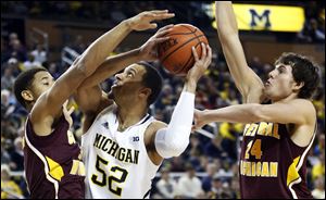 Michigan forward Jordan Morgan is defended by Central Michigan guard Derrick Richardson Jr., left, and forward Blake Hibbitts (24).