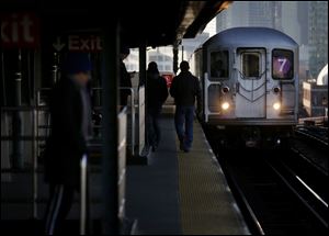 Commuters  walk on the platform as a train enters the 40th St-Lowry St Station, where a man was killed after being pushed onto the subway tracks, in the Queens section of New York, Friday.