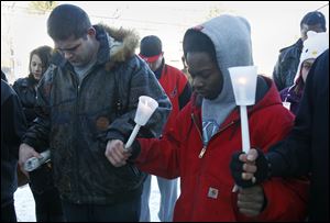 William Knop, left, and Devon Smith bow their heads at a candlelight vigil for Brian Minley, Jr., 24, who was shot and killed New Year’s Eve in his Berdan Avenue home.