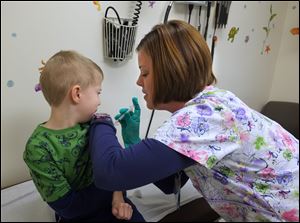 Licensed practical nurse Carrie Beebe administers a flu shot to Shane Zimmerman, 5, in the office of Dr. Colleen Olson, in Perrysburg on Friday. 